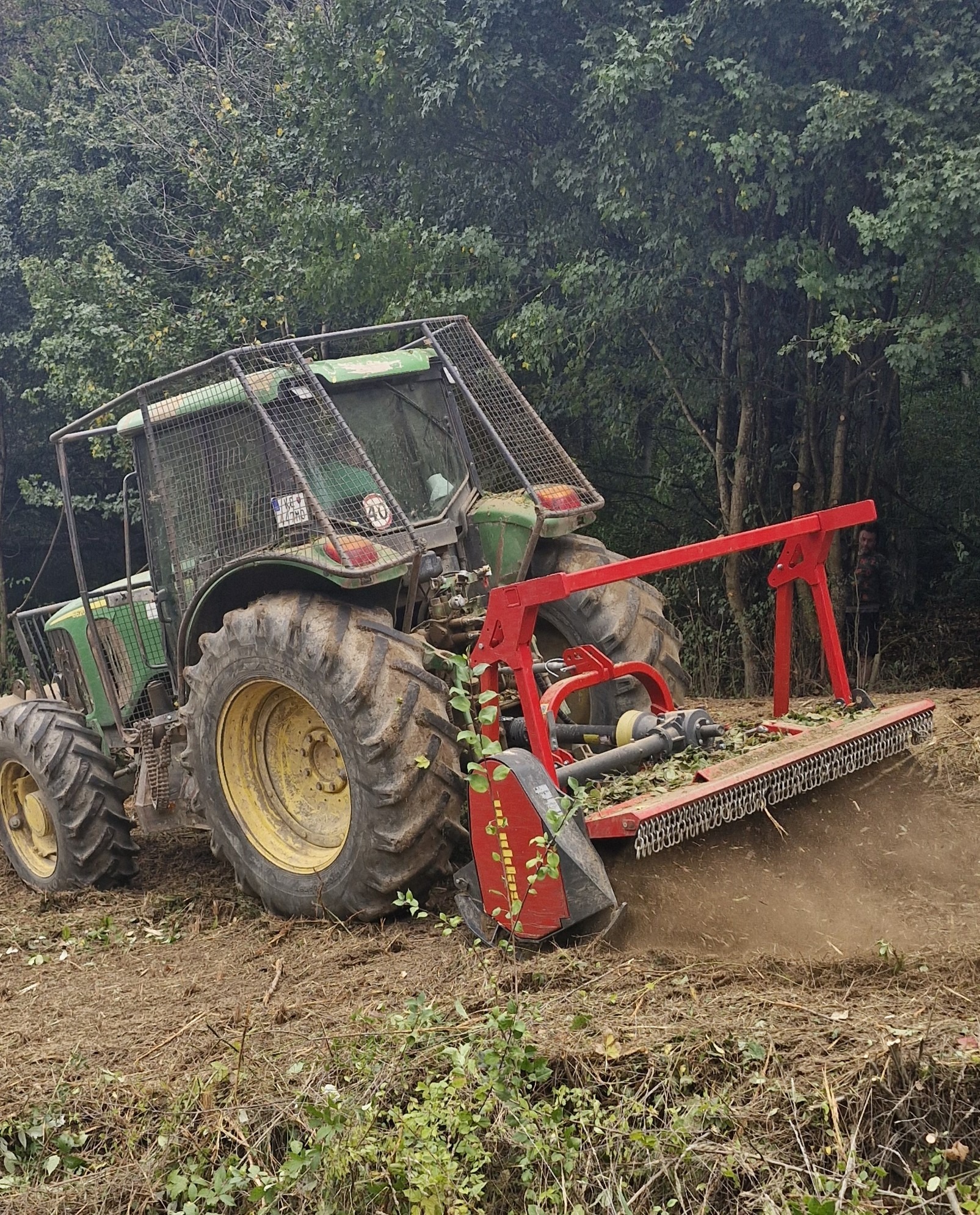 Traktor s lesnou frézou pri čistení zarasteného pozemku
